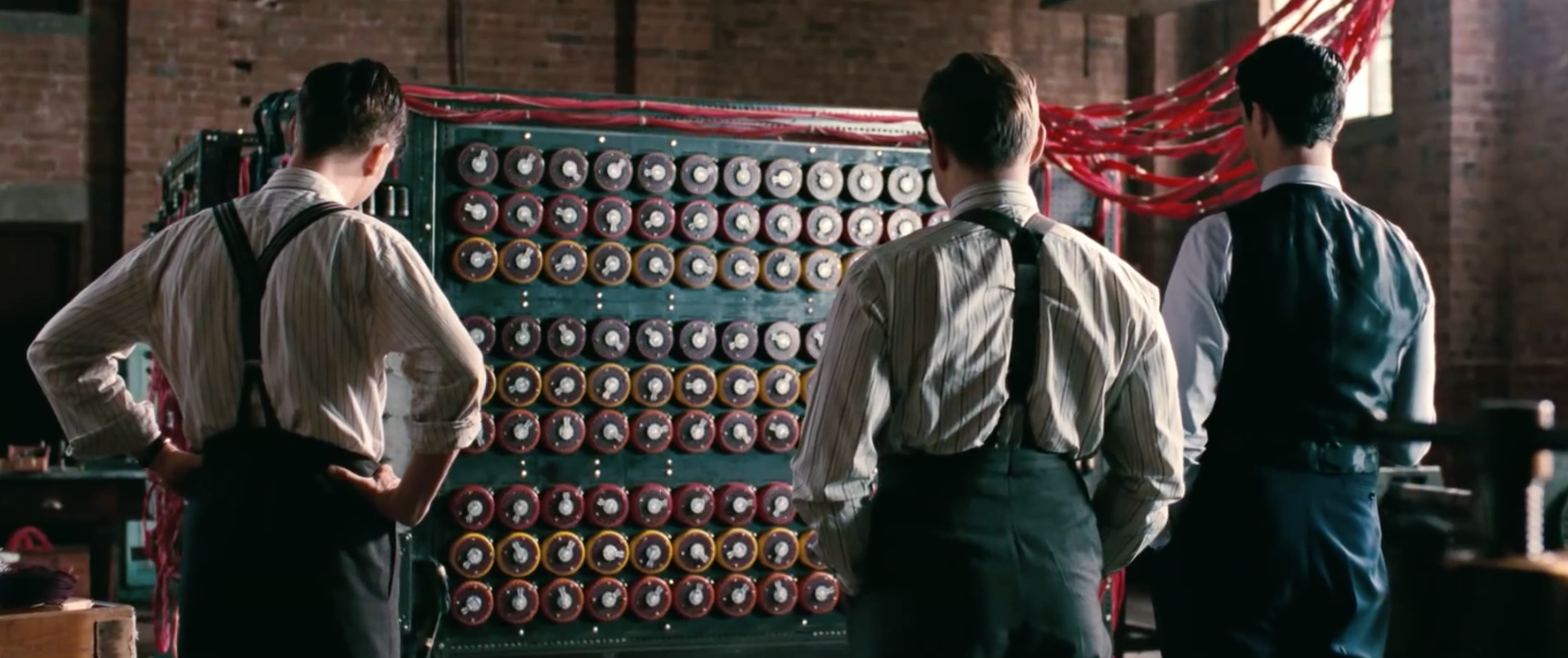 Alan Turing and team members at Bletchley Park, with a forerunner of the modern computer &mdash;  technology invented by brilliant people to break the Nazi Enigma encryption. Screenshot from official trailer, under fair use.